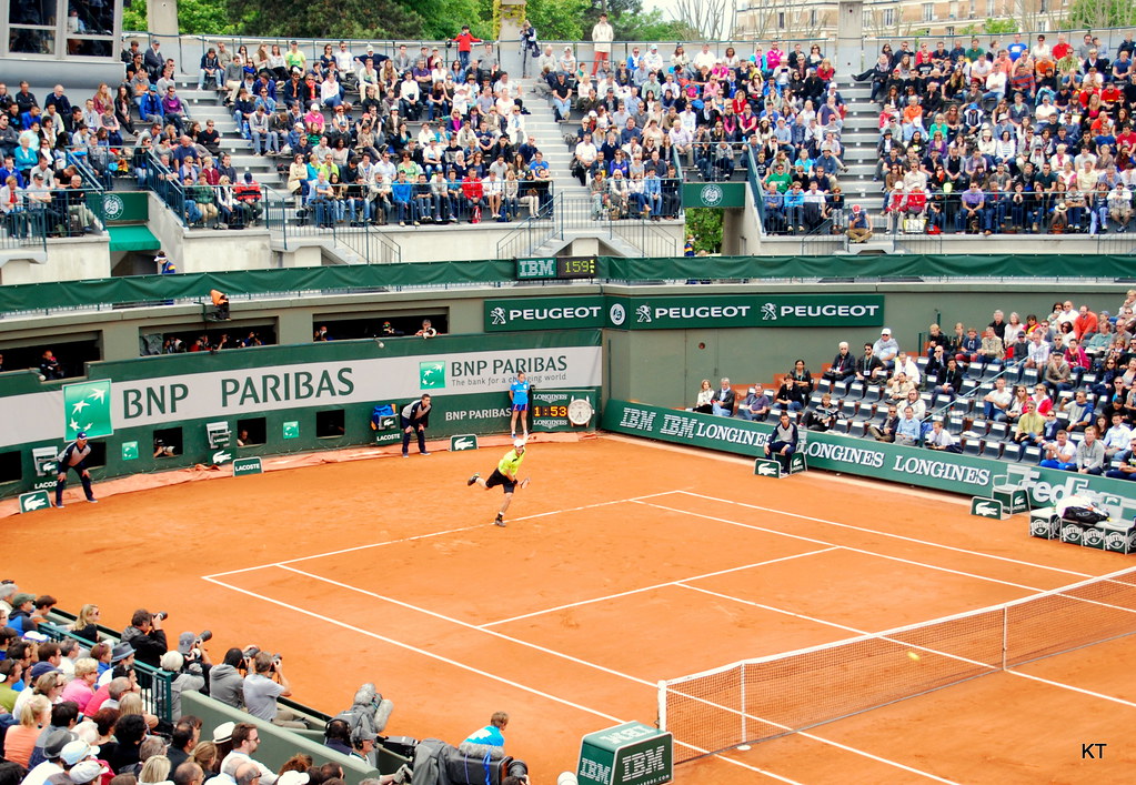Andy Murray playing at Roland Garros on a clay show court, with substantial run-off space visible behind the baseline and along the sidelines