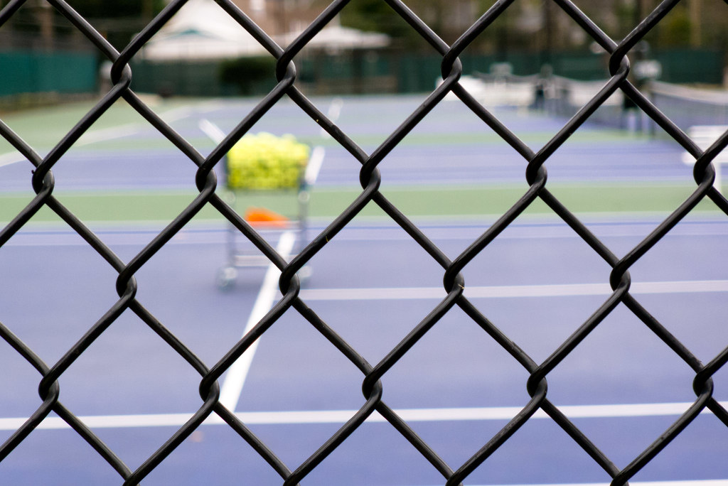 Public tennis court viewed through chain-link fence