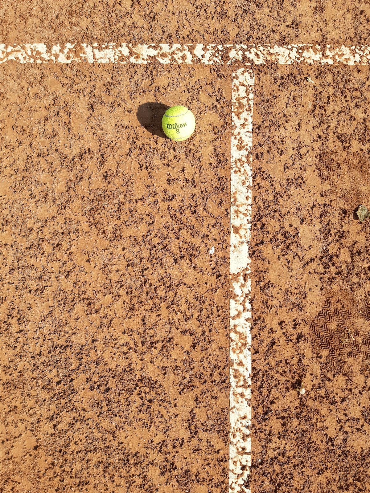 Tennis ball on a clay court surface