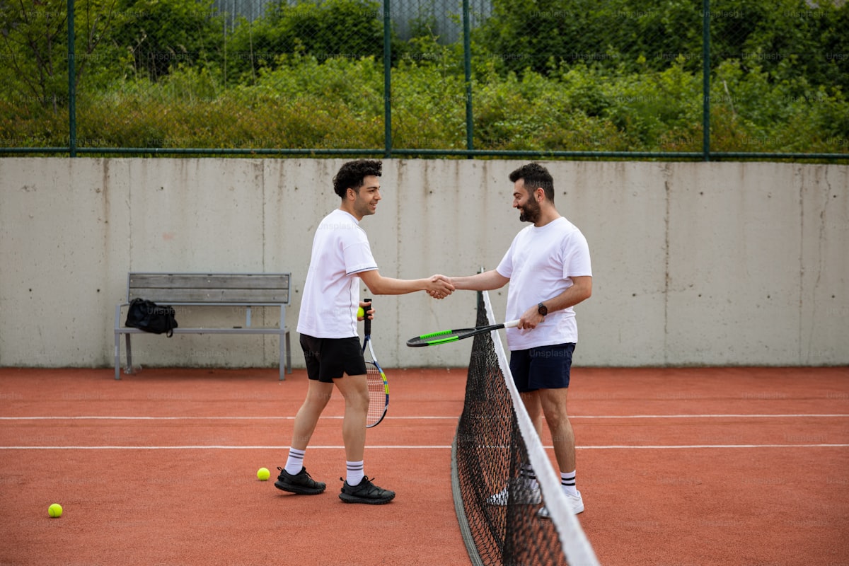 Two tennis players shaking hands over the net after a match